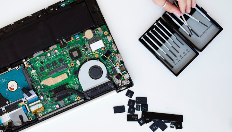 Laptop being disassembled for hardware repair, deep cleaning, or component upgrades, showing internal components and a technician at work.